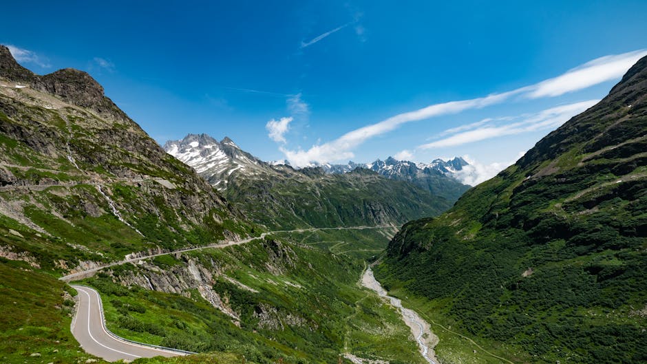 Breathtaking vista of Susten Pass with winding road in the Swiss Alps under a clear summer sky.
